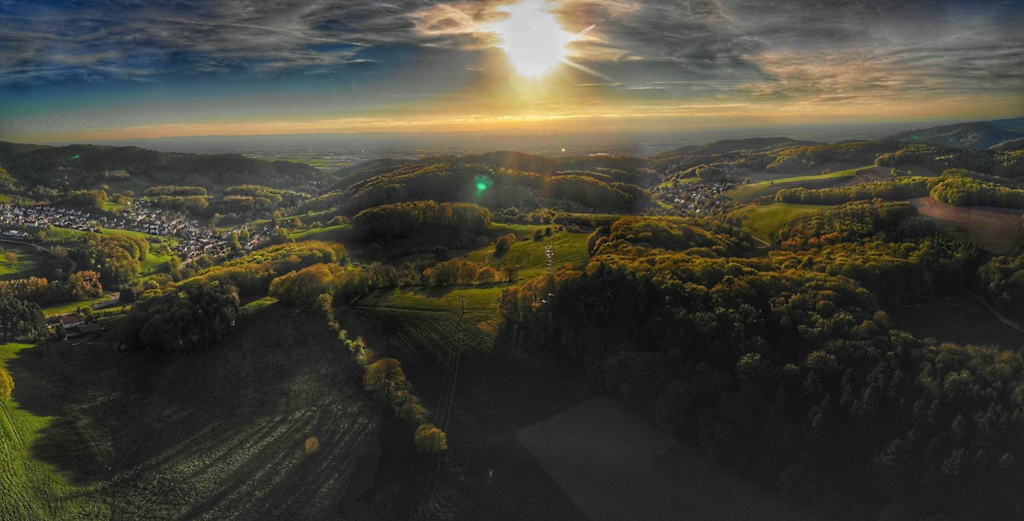 Il tramonto illumina un villaggio incastonato in una valle collinare.