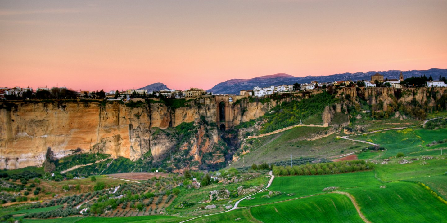 Borgo storico a picco sul mare, collegato da un ponte di pietra su una gola.